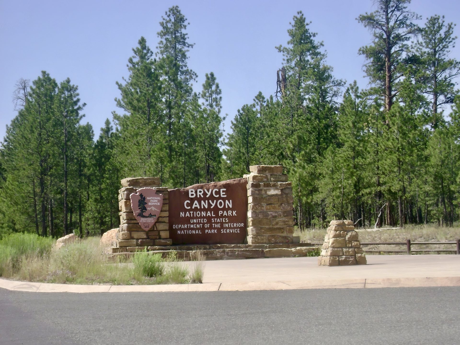 The stone entrance sign at Bryce Canyon National Park, pine forest behind it